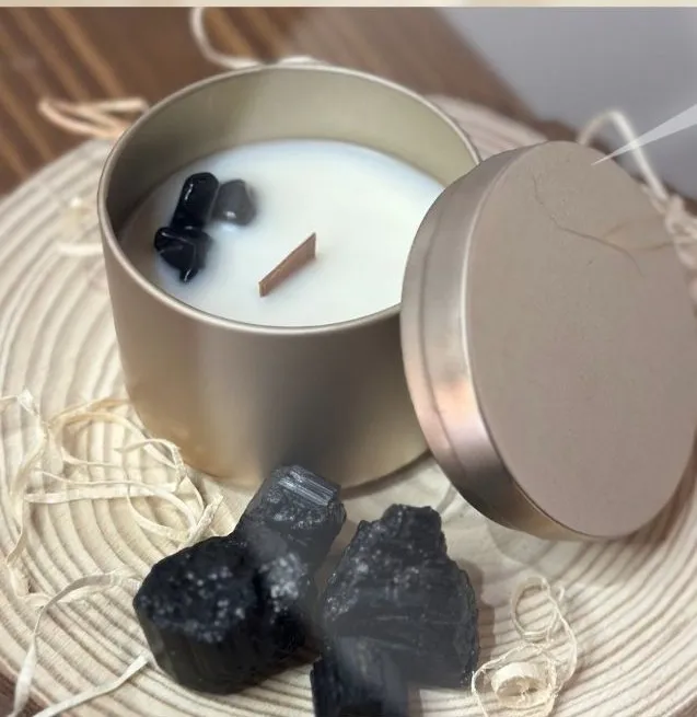 Candela in latta dorata con pietre di tormalina nera sulla cera, accanto a due grezzi di tormalina